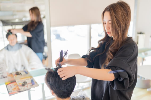 男性の髪をカットする女性